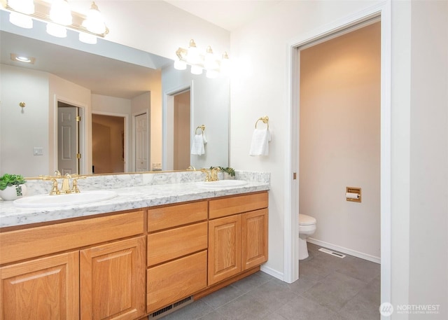 bathroom with visible vents, a sink, toilet, and double vanity