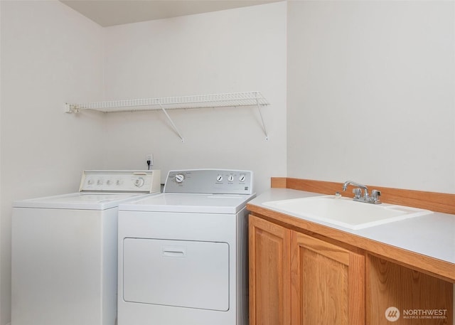 washroom with cabinet space, washing machine and dryer, and a sink