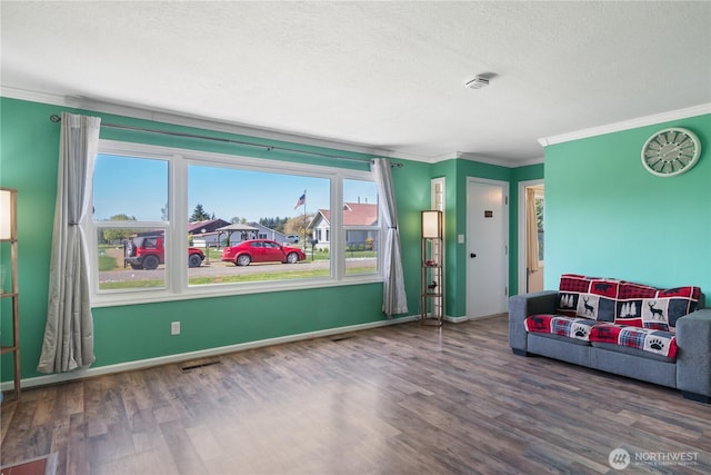 interior space with ornamental molding, visible vents, a textured ceiling, and wood finished floors