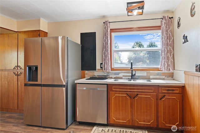 kitchen with light wood-style flooring, a sink, light countertops, appliances with stainless steel finishes, and brown cabinetry