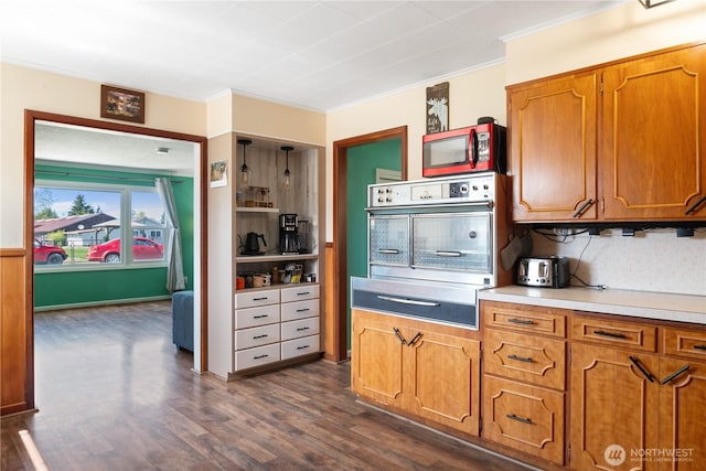 kitchen with oven, dark wood-style floors, light countertops, a warming drawer, and brown cabinetry