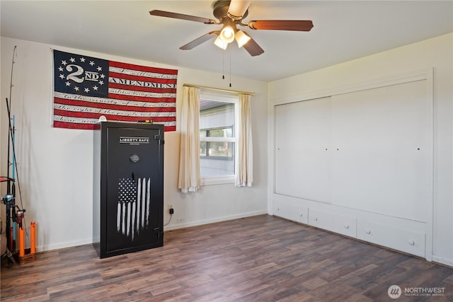 unfurnished room featuring dark wood-style floors, a ceiling fan, and baseboards