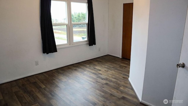 empty room featuring dark wood-style floors and baseboards