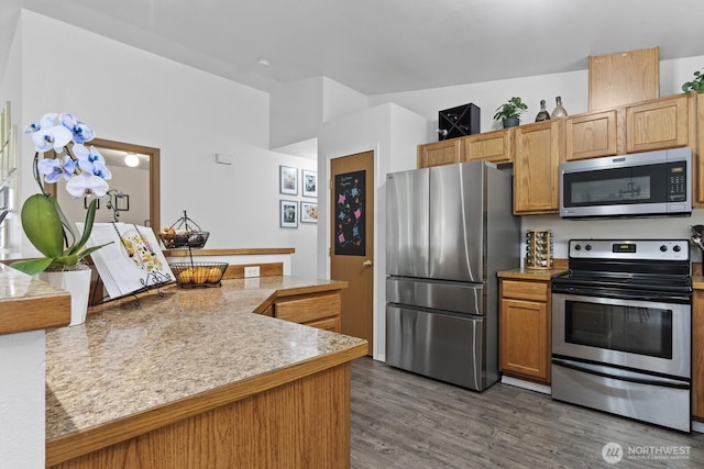 kitchen featuring lofted ceiling, stainless steel appliances, dark wood-style flooring, light countertops, and brown cabinets