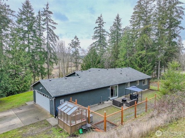 back of house featuring roof with shingles, fence, an outbuilding, and an exterior structure