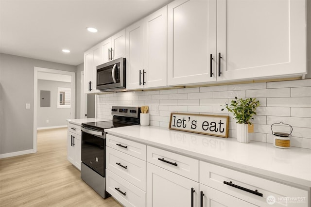 kitchen with light wood-style flooring, white cabinetry, light countertops, appliances with stainless steel finishes, and tasteful backsplash