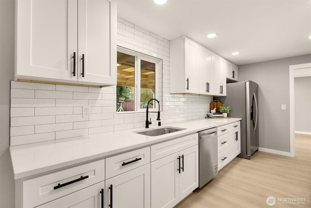 kitchen featuring white cabinets, appliances with stainless steel finishes, light countertops, and a sink