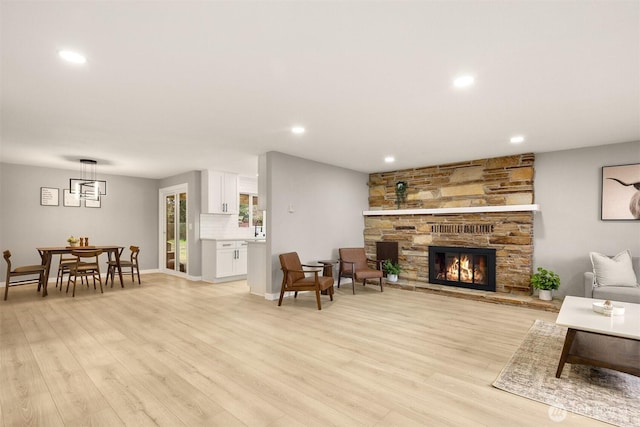 living area with recessed lighting, a fireplace, light wood-style flooring, and baseboards