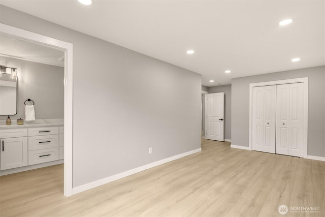 unfurnished bedroom featuring baseboards, ensuite bathroom, light wood-style floors, a closet, and recessed lighting