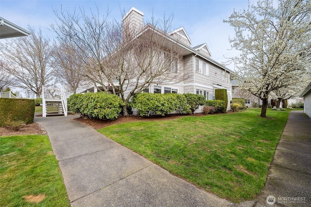 view of front of house featuring a chimney, stairway, and a front yard