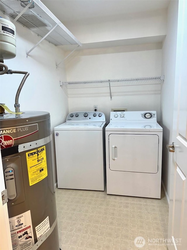 clothes washing area with washing machine and dryer, strapped water heater, and laundry area