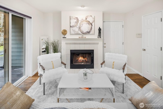 living area with a fireplace, baseboards, and wood finished floors