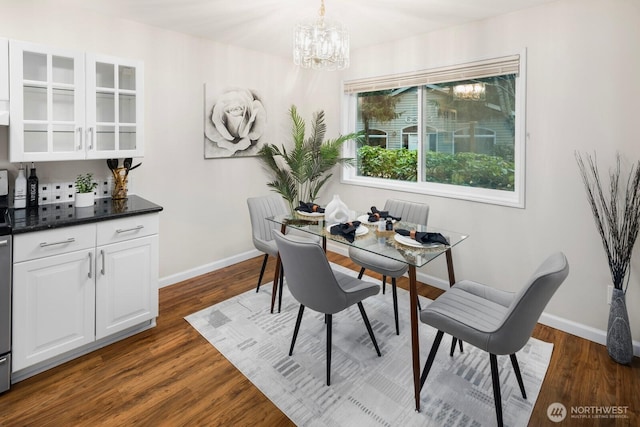 dining space with baseboards, a chandelier, and dark wood-style flooring