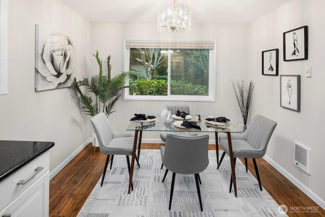 dining area with heating unit, light wood-style flooring, baseboards, and a chandelier