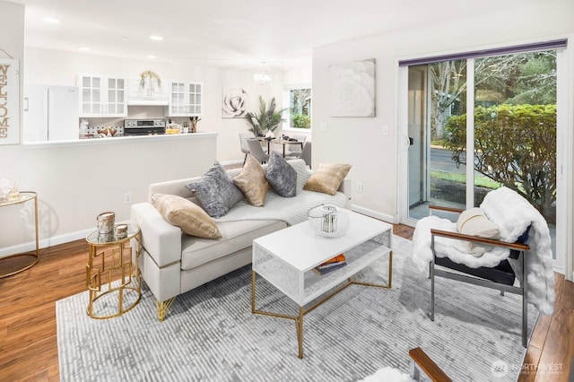 living room featuring recessed lighting, an inviting chandelier, baseboards, and wood finished floors