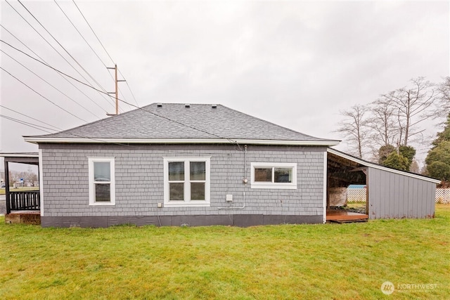 rear view of property with a shingled roof and a yard