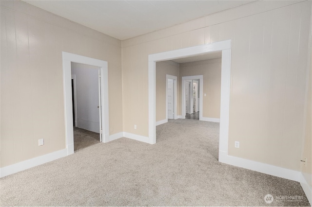 empty room featuring light colored carpet and baseboards