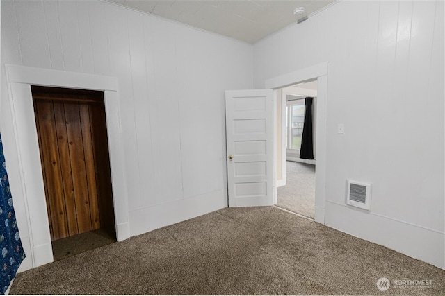 spare room featuring dark colored carpet and visible vents