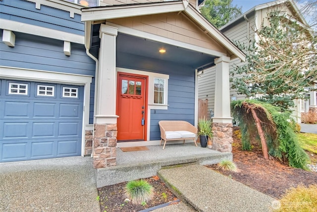 entrance to property featuring a garage, stone siding, and covered porch