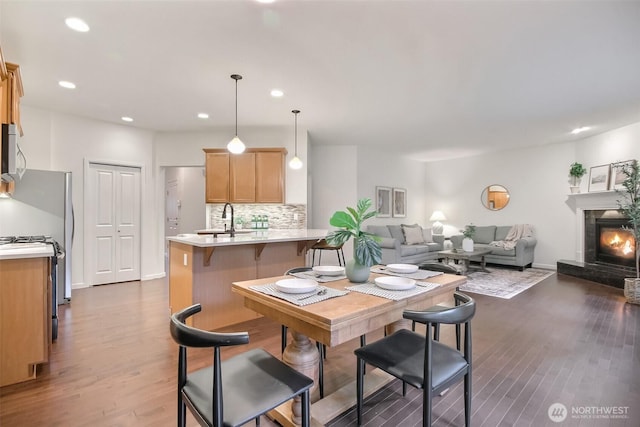 dining space featuring dark wood-type flooring, recessed lighting, and a lit fireplace