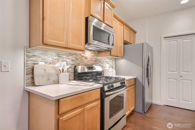 kitchen with stainless steel appliances, light brown cabinetry, light countertops, and tasteful backsplash