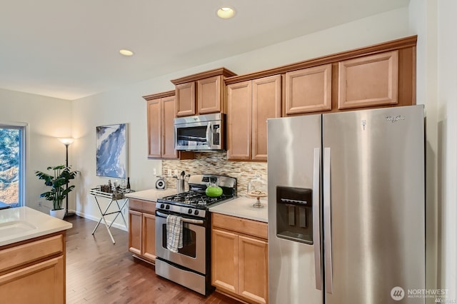 kitchen featuring light wood finished floors, tasteful backsplash, recessed lighting, light countertops, and appliances with stainless steel finishes