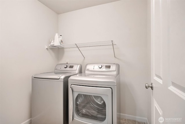 washroom featuring laundry area, washing machine and dryer, and baseboards