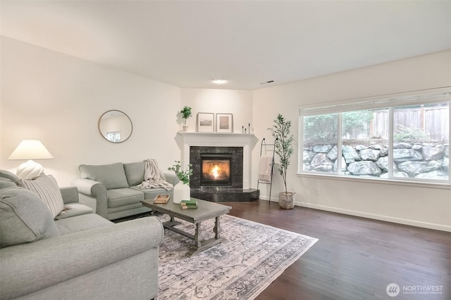 living area with visible vents, a premium fireplace, baseboards, and dark wood-type flooring