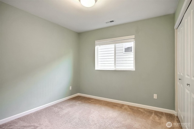 unfurnished room with carpet floors, visible vents, and baseboards