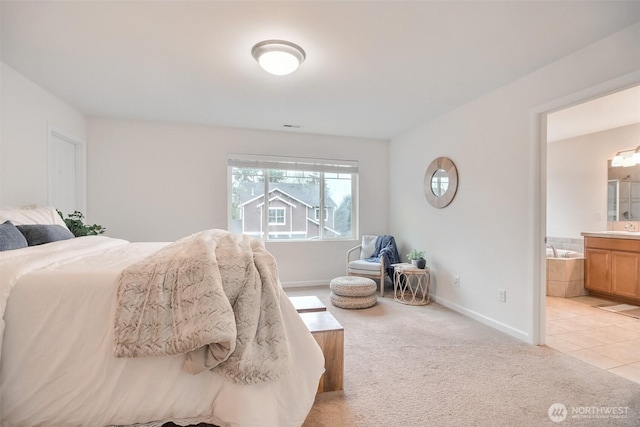 bedroom with light carpet, baseboards, and ensuite bathroom