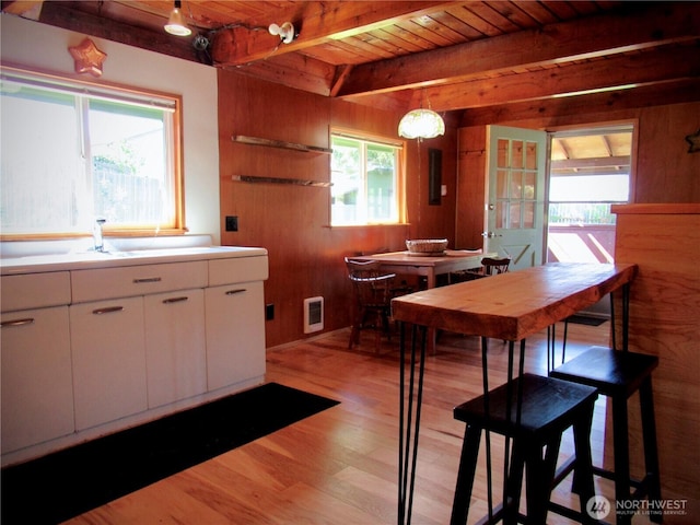 845 Schmid Rd, Grayland, WA 98547 - kitchen featuring wooden ceiling, light wood-style floors, beamed ceiling, wood walls, and white cabinetry