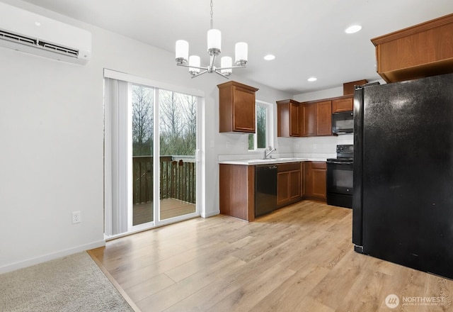 kitchen featuring hanging light fixtures, light countertops, an AC wall unit, black appliances, and brown cabinetry