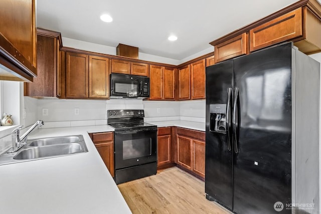 kitchen with brown cabinets, light countertops, a sink, and black appliances