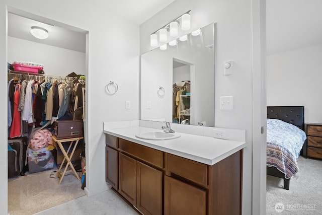 bathroom with ensuite bath, a walk in closet, and vanity