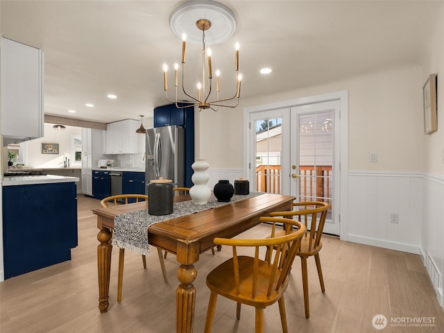 dining area featuring a wealth of natural light, french doors, wainscoting, and light wood-style flooring