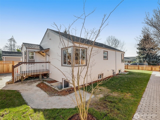 view of home's exterior with fence, a deck, and a yard