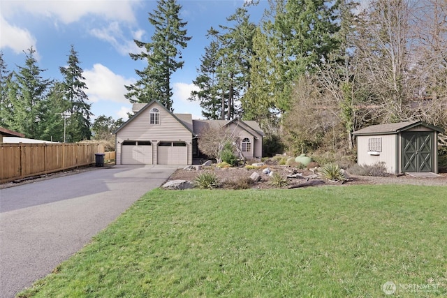 view of front facade featuring a storage unit, a front lawn, fence, and aphalt driveway