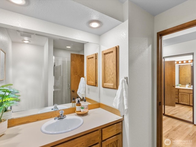 bathroom with a stall shower, vanity, and wood finished floors