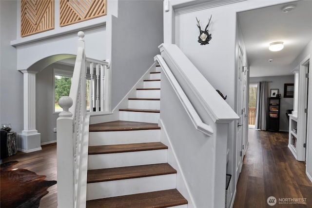 stairs featuring a wealth of natural light, ornate columns, and wood finished floors