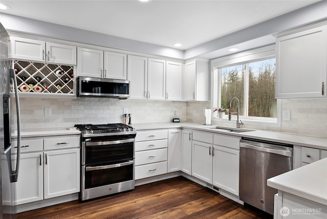 kitchen featuring white cabinets, dark wood finished floors, stainless steel appliances, light countertops, and a sink