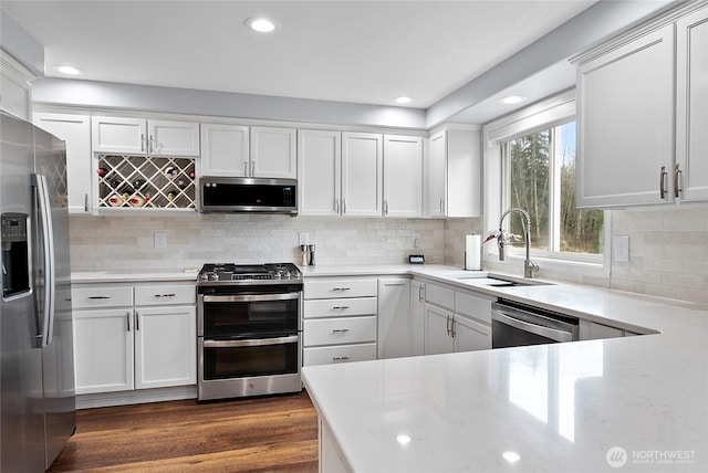 kitchen featuring dark wood finished floors, white cabinetry, stainless steel appliances, and a sink