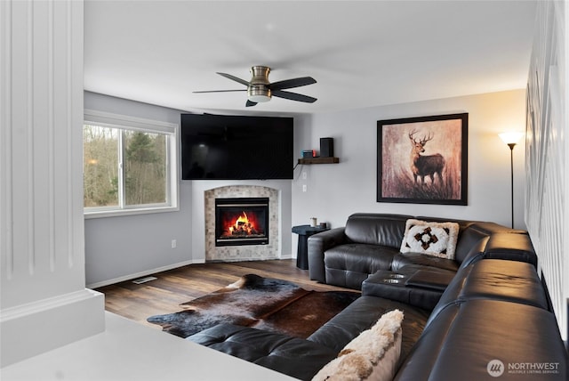 living room with baseboards, visible vents, ceiling fan, wood finished floors, and a fireplace