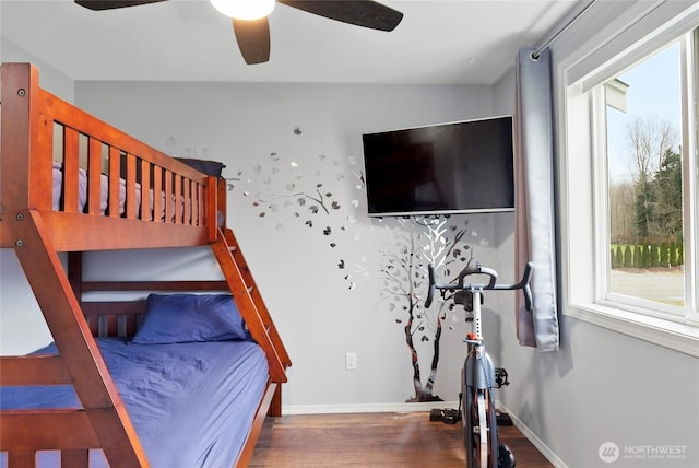 bedroom with dark wood-style floors, a ceiling fan, and baseboards