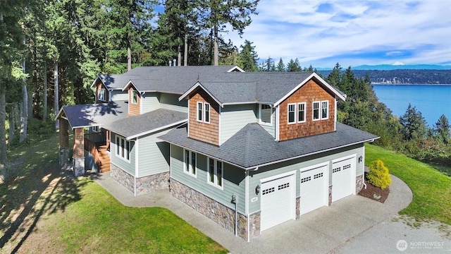 view of front of house featuring a shingled roof, stone siding, and a front lawn