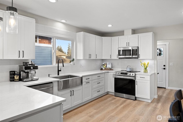 kitchen featuring appliances with stainless steel finishes, white cabinets, and light countertops