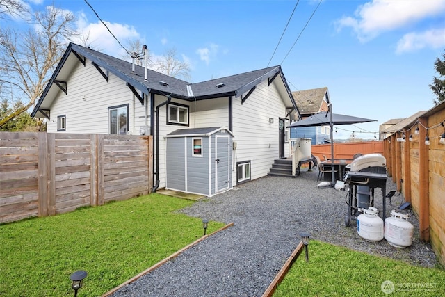 rear view of property with an outbuilding, a storage unit, a lawn, and a fenced backyard