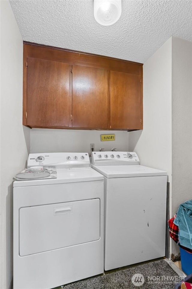 laundry room featuring a textured ceiling, washer and clothes dryer, and cabinet space