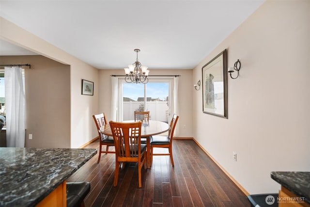 dining area featuring baseboards, a chandelier, and dark wood-type flooring