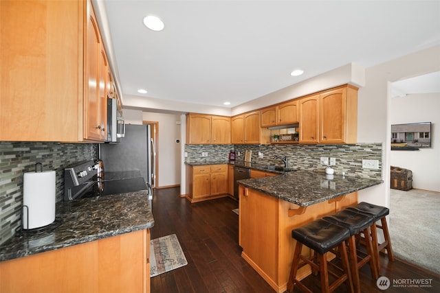 kitchen with dark wood-style flooring, recessed lighting, decorative backsplash, stainless steel range with electric cooktop, and a peninsula