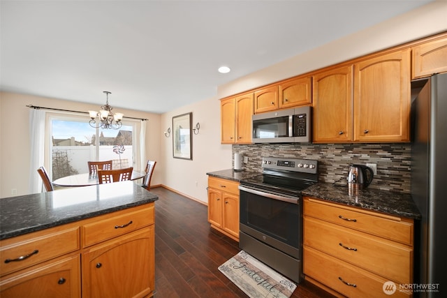 kitchen with pendant lighting, dark wood-style flooring, stainless steel appliances, backsplash, and dark stone countertops